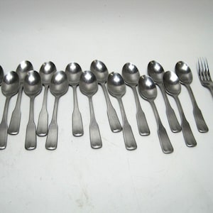 May include: A set of 15 silver spoons and a fork. The spoons are arranged in a row, with the fork at the end. The spoons are all the same size and shape, and they have a simple, elegant design.