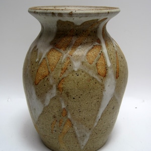 May include: A ceramic vase with a brown, white, and gold glaze. The vase has a rounded body and a narrow neck.