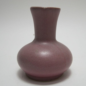 May include: A small, light pink ceramic vase with a rounded body and a narrow neck.