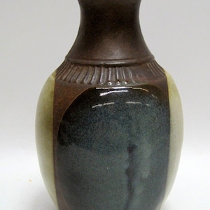May include: A brown and cream ceramic vase with a dark blue glaze. The vase has a rounded body and a narrow neck.