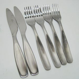 May include: Set of seven silver-toned flatware pieces, including two butter knives and five forks.