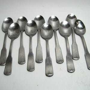 May include: A set of 10 silver teaspoons with rounded bowls and simple handles.