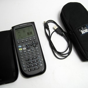 May include: A black TI-89 Titanium graphing calculator with a protective cover, a black carrying case, and a USB cable. The calculator has a screen displaying various icons and functions. The carrying case has the word "IDEAL" printed on it.