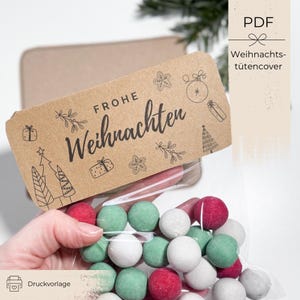 Puede incluir: Una bolsa transparente llena de caramelos redondos rojos, verdes y blancos. Una etiqueta de papel kraft con las palabras "Frohe Weihnachten" e ilustraciones navideñas está adjunta. La etiqueta también tiene el texto "Weihnachtstütencover".