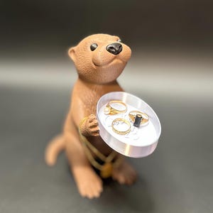 A cute otter-shaped jewelry holder with a trinket dish, available in multiple colors for added charm.