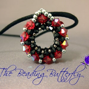 May include: A red and black beaded necklace with a silver accent. The necklace is in the shape of a circle and is hanging from a black cord.