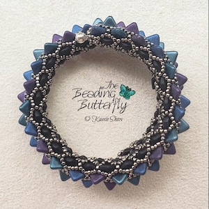 Könnte beinhalten: Ein Armband aus Perlen mit einer schwarzen und silbernen Basis und blauen, violetten und türkisfarbenen dreieckigen Perlen. Das Armband hat die Form eines Kreises und einen Verschluss.