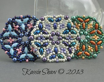 Könnte beinhalten: Drei runde Perlenornamente mit komplizierten geometrischen Mustern. Das Ornament links ist blau, rosa und silber. Das mittlere Ornament ist silber, blau und lila. Das Ornament rechts ist grün, braun und gold.