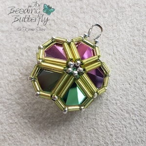 Può includere: Un ciondolo di perline verdi, rosa e argento con un anello d'argento per appenderlo. Il ciondolo ha la forma di un fiore a sei petali.