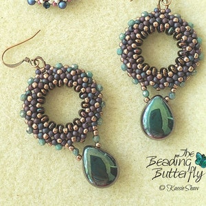 May include: A pair of earrings with a teardrop-shaped pendant. The earrings are made of brown and green beads and have a copper wire loop. The teardrop pendant is a dark green color with a metallic sheen.