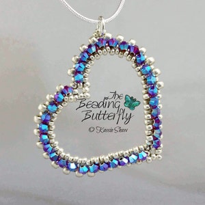 May include: A silver and iridescent blue heart-shaped pendant necklace. The pendant is made of small beads and has a delicate, intricate design. The necklace is attached to a silver chain.