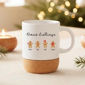 May include: A white ceramic mug with a cork base featuring the text Omas Lieblinge and four gingerbread person illustrations labeled Helene, Oskar, Bella, and Leonard. The gingerbread figures have distinct accessories including a candy cane, a red bow, and a red scarf.