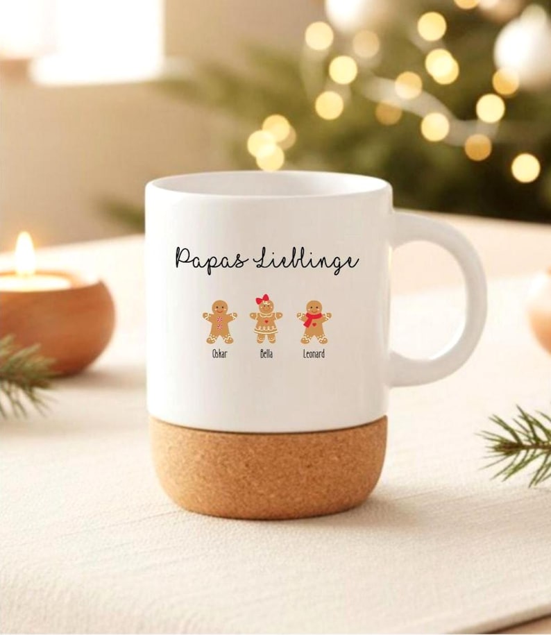 May include: A white ceramic mug with a cork base featuring the black text Papas Lieblinge and three gingerbread cookie illustrations labeled Oskar, Bella, and Leonard. The middle gingerbread figure wears a red bow, and the right figure wears a red scarf.