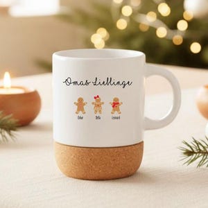 May include: A white ceramic mug with a cork base featuring the black text Omas Lieblinge and three gingerbread cookie illustrations labeled Oskar, Bella, and Leonard. The middle gingerbread figure wears a red bow, and the right one wears a red scarf.