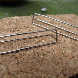 May include: Two silver rectangle shaped earrings with a minimalist design.