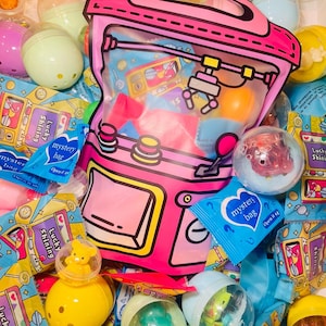 Peut inclure: Image vibrante d'un sac rose de style dessin animé rempli de jouets colorés et de sacs mystères. Le sac a une face transparente, montrant un design de machine à griffes. Autour du sac, divers jouets en capsule et des sacs mystères bleus avec le texte "mystery bag".