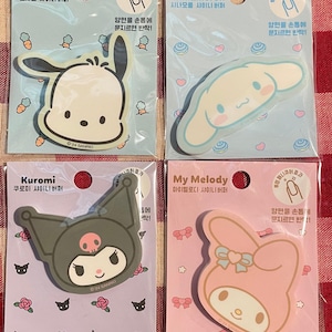 May include: Four Sanrio character nail buffers. The top left features a white rabbit with black accents. The top right shows a light blue character. The bottom left is a dark grey character. The bottom right is a pink character.