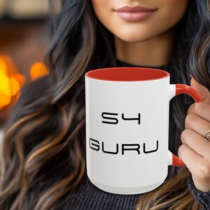 May include: White ceramic coffee mug with a red rim and handle. The mug has black text that reads "S4 GURU".