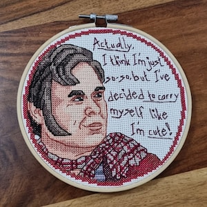 Può includere: Arte ricamata a forma di cerchio con un ritratto di una persona con capelli castani e una sciarpa a quadri rossi e bianchi. Il testo dice "In realtà, penso di essere solo così così, ma ho deciso di portarmi come se fossi carino!"
