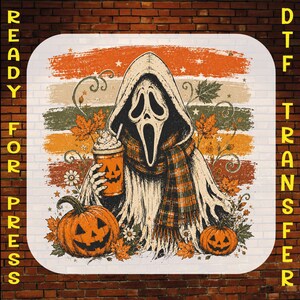 May include: A graphic print featuring a hooded figure with a ghost mask holding a pumpkin-faced cup, surrounded by autumn leaves, flowers, and two jack-o'-lanterns. The background consists of horizontal stripes in orange, green, and brown tones.