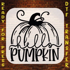 May include: A black graphic design on a white background featuring a stylized pumpkin illustration with the text hello PUMPKIN. The words READY FOR PRESS DTF TRANSFER are printed in yellow on the left and right sides of the white square.