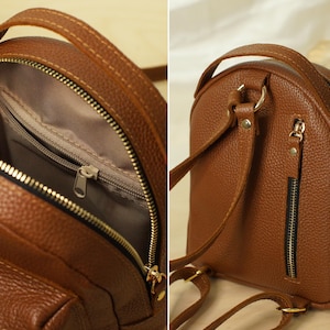May include: A brown textured mini backpack featuring a top handle, adjustable shoulder straps, and gold-tone hardware. The interior is lined with fabric and includes a zippered pocket, while the exterior back panel features a vertical zippered pocket.
