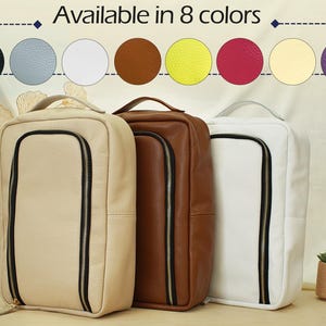 May include: Three rectangular bags with textured surfaces in beige, brown, and white. Each bag features a vertical black zippered front compartment and a top handle. The image includes text stating Available in 8 colors with circular swatches.