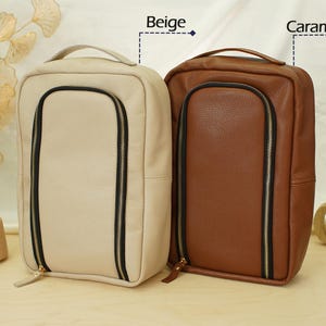 May include: Two rectangular bags with top handles and a U-shaped front zipper closure. One bag is beige and the other is caramel brown. Both feature a textured surface, black zipper tape, and gold-toned zipper pulls. The text Beige and Caramel appear.