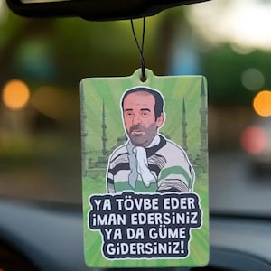 May include: Green rectangular car air freshener with a cartoon image of a man wearing a striped shirt and a white scarf. The air freshener has text in white and green that reads "YA TÖVBE EDER İMAN EDERSİNİZ YA DA GÜME GİDERSİNİZ!"