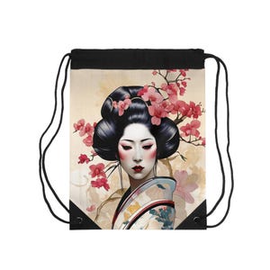 Puede incluir: Mochila con cordón negra con una ilustración de geisha. La geisha tiene cabello oscuro, labios rojos y está adornada con flores de cerezo rosas. El fondo es de un tono suave y neutro, y la bolsa tiene cordones negros.