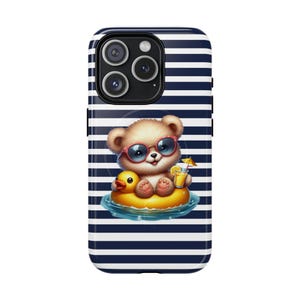 May include: A phone case with a navy blue and white striped pattern. The case features a cartoon bear wearing sunglasses and floating on a yellow duck-shaped inflatable ring. The bear is holding a drink with a tiny umbrella.