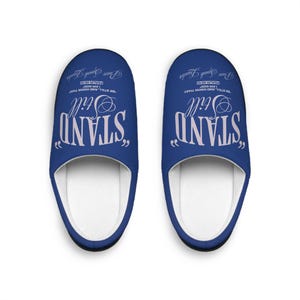 Puede incluir: Un par de zapatillas azules con interiores blancos. Las zapatillas presentan las palabras "STAND Still" en una fuente estilizada, junto con el texto "BE STILL AND KNOW THAT I AM GOD, PSALM 46:10" y "Peace Speak Lender".