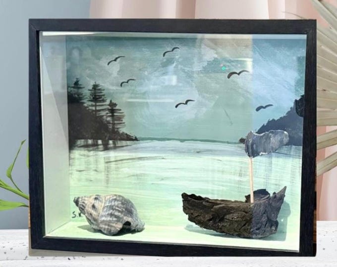 Maritime gift with North Sea driftwood and Baltic Sea beach finds in a hand-painted picture frame. Featuring a ship by the sea motif.