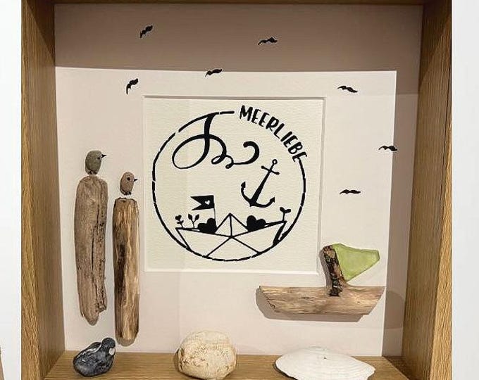 A maritime stone picture featuring Baltic Sea beach finds lovingly arranged in a picture frame. A plotter gift featuring North Sea driftwood.