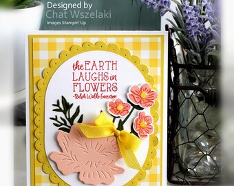 May include: A handmade greeting card featuring a yellow and white gingham background, a scalloped oval frame, and the text "the EARTH LAUGHS in FLOWERS -Ralph Waldo Emerson". It includes a peach-coloured die-cut flower, a yellow ribbon, and small pink flowers.