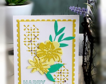 May include: A rectangular greeting card with a yellow postage stamp-style border on a white base. The card features layered yellow paper flowers, green paper leaves, and intricate die-cut patterns accented with small clear rhinestones. The text HAPPY BIRTHDAY! is printed in teal at the bottom left corner.