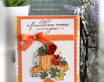 May include: A rectangular greeting card with a scalloped orange border and a white embossed background. The text reads IF friends WERE PUMPKINS I'D PICK you. It features an orange ribbon bow and a die-cut illustration of three orange pumpkins with green leaves and a yellow flower.