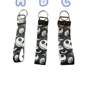 Può includere: Tre portachiavi con un motivo in bianco e nero di Jack Skellington. Ogni portachiavi ha un anello in metallo argentato e un passante in tessuto. Le lettere A, B e C sono sopra ogni portachiavi.