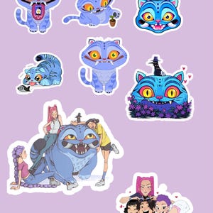 Op de afbeelding: Een verzameling cartoon kattenstickers in verschillende poses en ontwerpen. De katten zijn voornamelijk blauw met gele ogen en scherpe tanden. Sommige stickers bevatten extra karakters en bloemelementen.