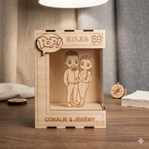 Peut inclure: Une boîte d'exposition en bois avec un logo Pop! et la date 30.05.2026. À l'intérieur, une illustration découpée au laser d'un couple. La boîte est gravée des noms "CORALIE & JÉREMY".