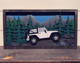 Puede incluir: Un Jeep blanco conduciendo por un paisaje de bosque. El Jeep está rodeado de árboles verdes y rocas grises. La escena está enmarcada en un marco de madera oscura.