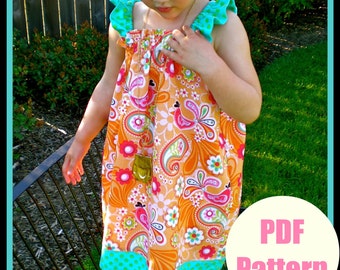 May include: A PDF pattern for a sleeveless dress with a bright orange, pink, and white floral print. The dress has a turquoise and white polka dot trim and ruffles on the straps. The dress is being modeled by a child.