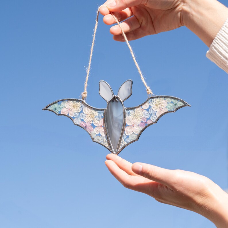 Gray stained glass bat with pastel blue and pink dried flowers in wings