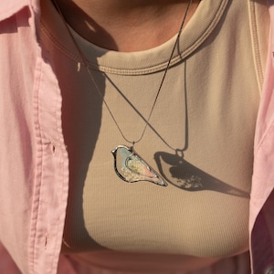 Close-up of nature-inspired necklace with hydrangea and wild blooms inside glass.