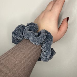 Può includere: Un elastico per capelli grigio e soffice fatto di filato.