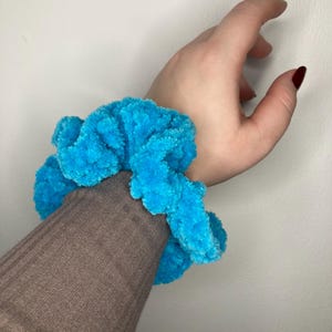 Può includere: Un elastico per capelli soffice e blu brillante.