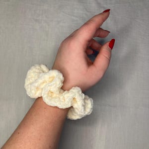 Può includere: Un elastico per capelli in crochet bianco con una texture soffice.