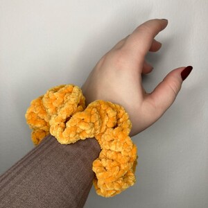 Può includere: Un elastico per capelli soffice di colore giallo brillante.