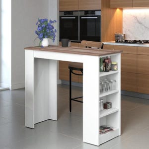 Könnte beinhalten: Eine weiße Kücheninsel mit einer braunen Holz-Arbeitsplatte. Die Insel hat offene Regale auf einer Seite, in denen Gläser und andere Gegenstände ausgestellt sind. Eine Vase mit blauen Blumen steht auf der Arbeitsplatte. In einer modernen Küche.
