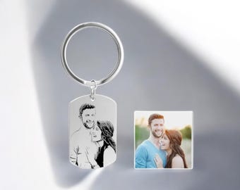 May include: A silver keychain with a rectangular tag featuring a black and white engraved image of a couple. The keychain also includes a smaller photo of the couple.